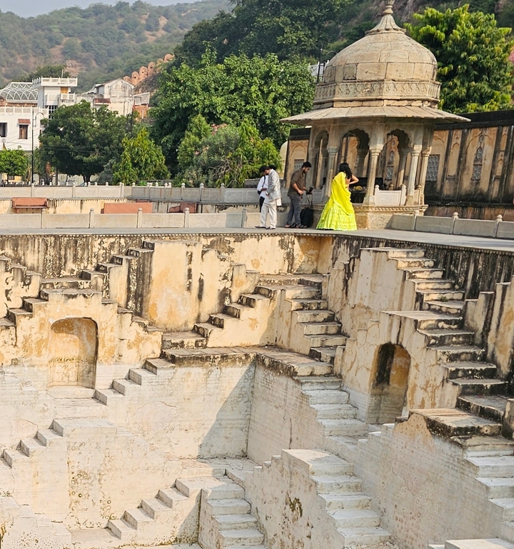 Des gens marchant près d'anciens puits à degrés à l'architecture complexe.