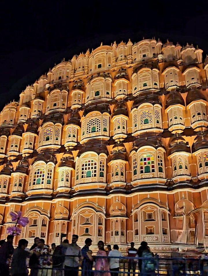 Façade illuminée d'un bâtiment avec plusieurs fenêtres la nuit.
