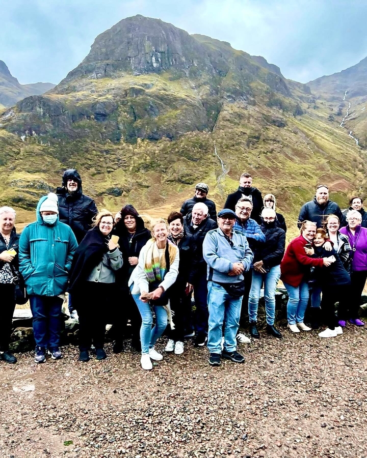 Un groupe de personnes posant devant un paysage vallonné.