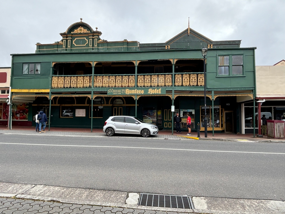 Un bâtiment historique appelé Hunter's Hotel avec des personnes et une voiture garée devant.