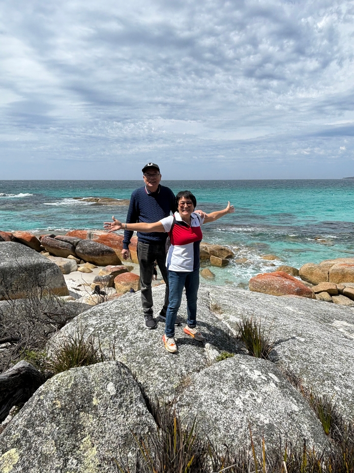 Deux personnes posant sur une plage avec des eaux bleues claires.