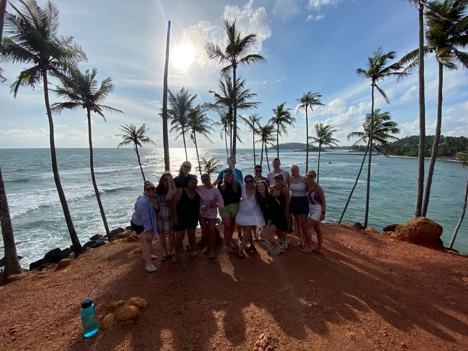 Groupe de personnes posant devant des palmiers au bord de l'océan