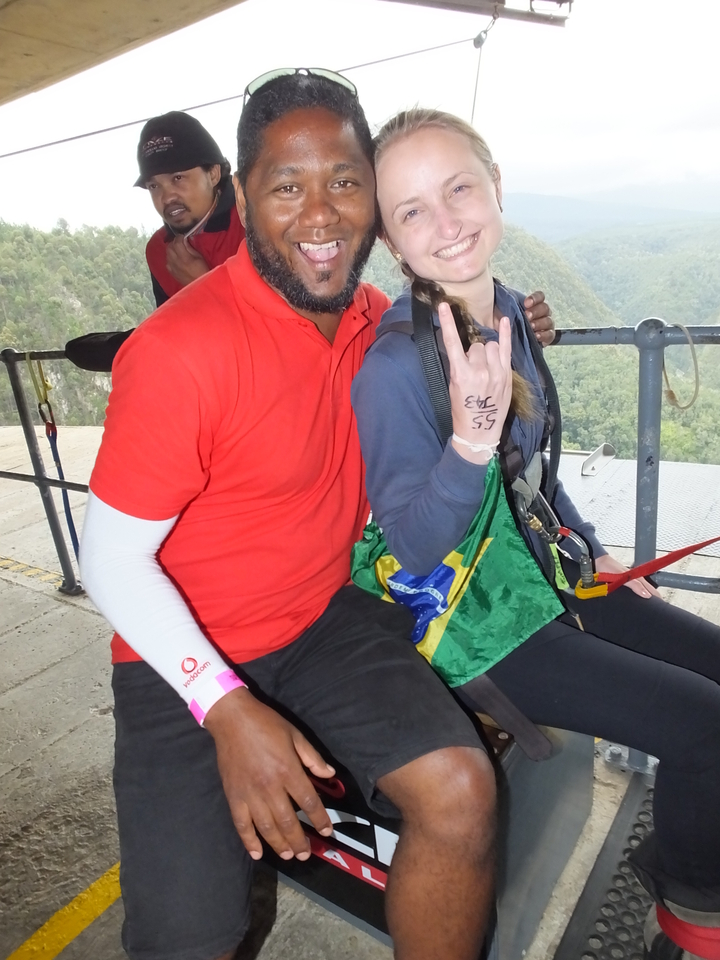 Deux personnes en tenue de plein air posant pour une photo sur fond de paysage.