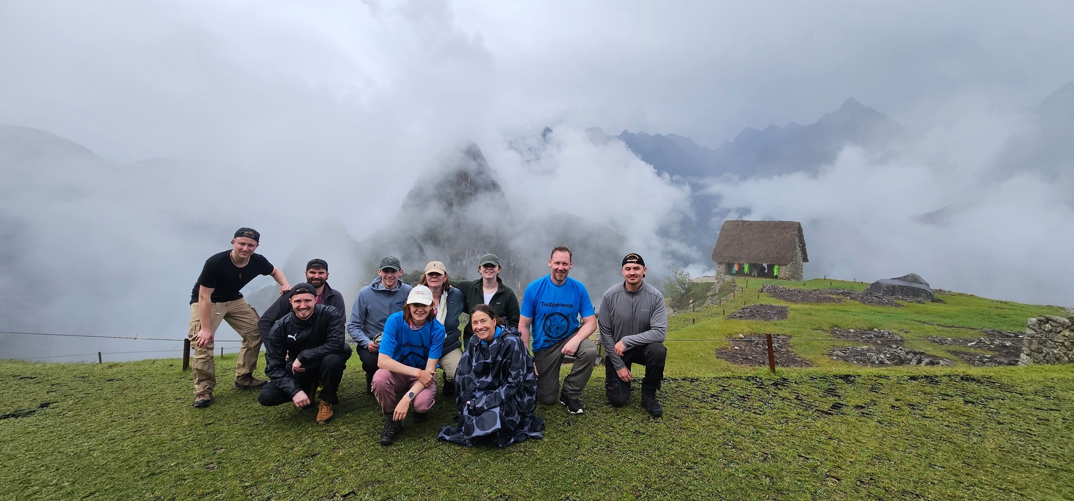 Groupe de personnes posant sur une colline herbeuse dans les nuages.