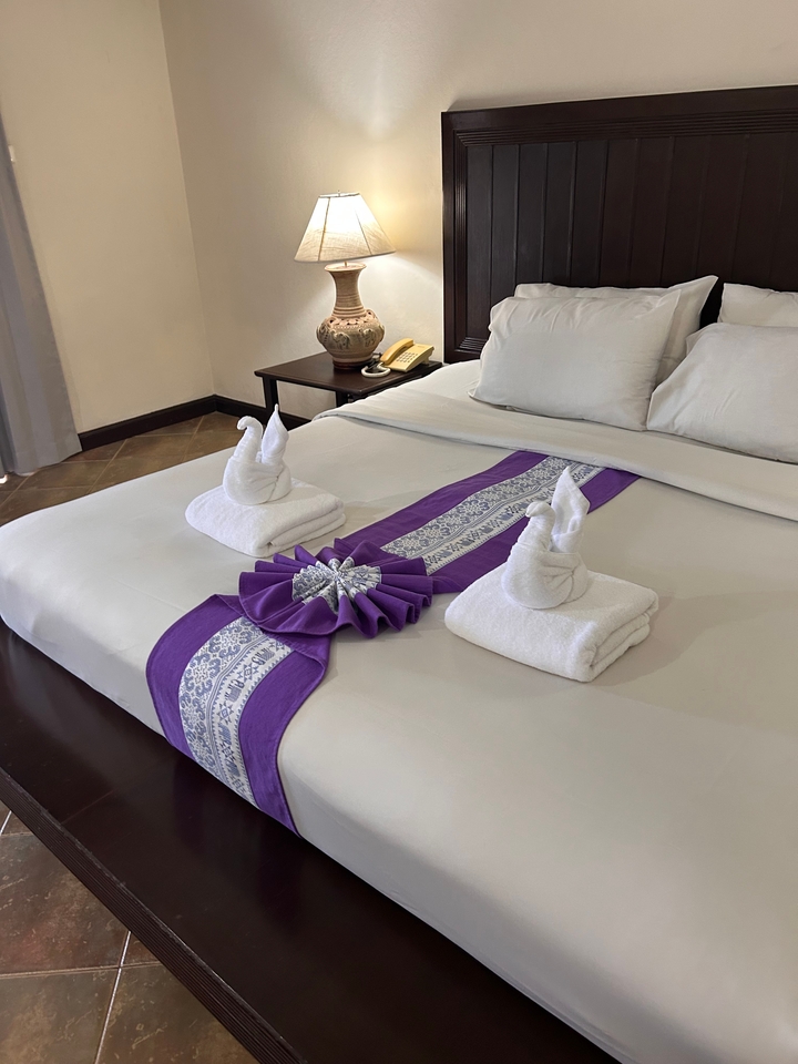 Une chambre d'hôtel avec des serviettes soigneusement arrangées et des décorations sur un lit.