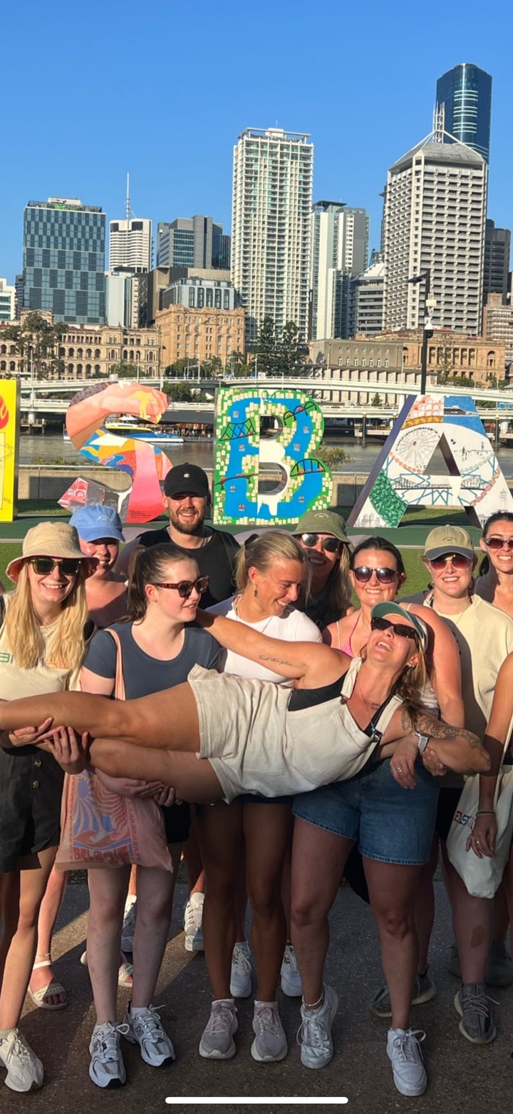 Groupe de personnes posant devant un panneau coloré de Brisbane.