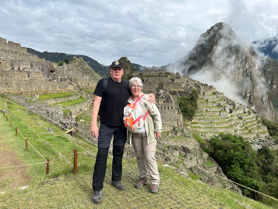 Touristen, die mit Ruinen und nebligen Bergen im Hintergrund posieren.
