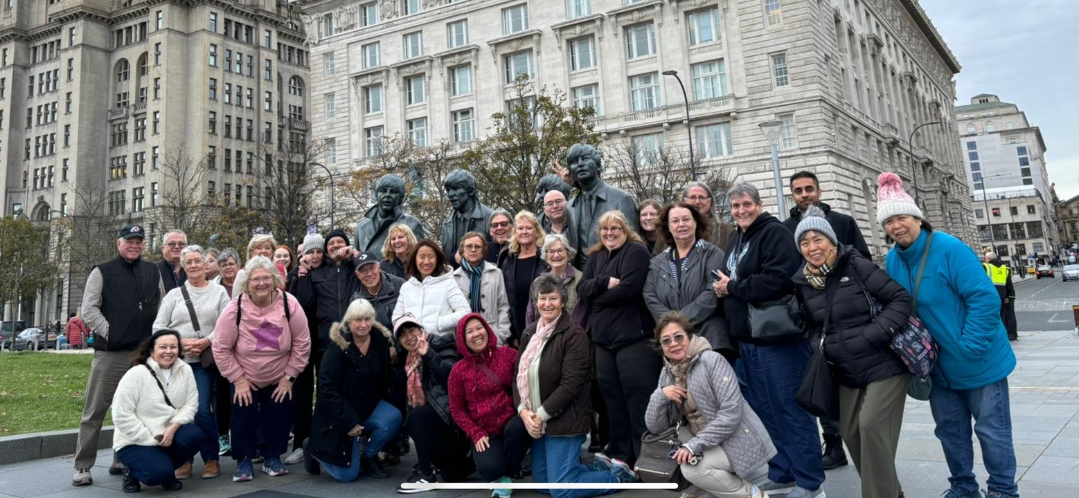 Eine große Gruppe von Menschen, die vor Statuen und einem prächtigen Gebäude posiert.