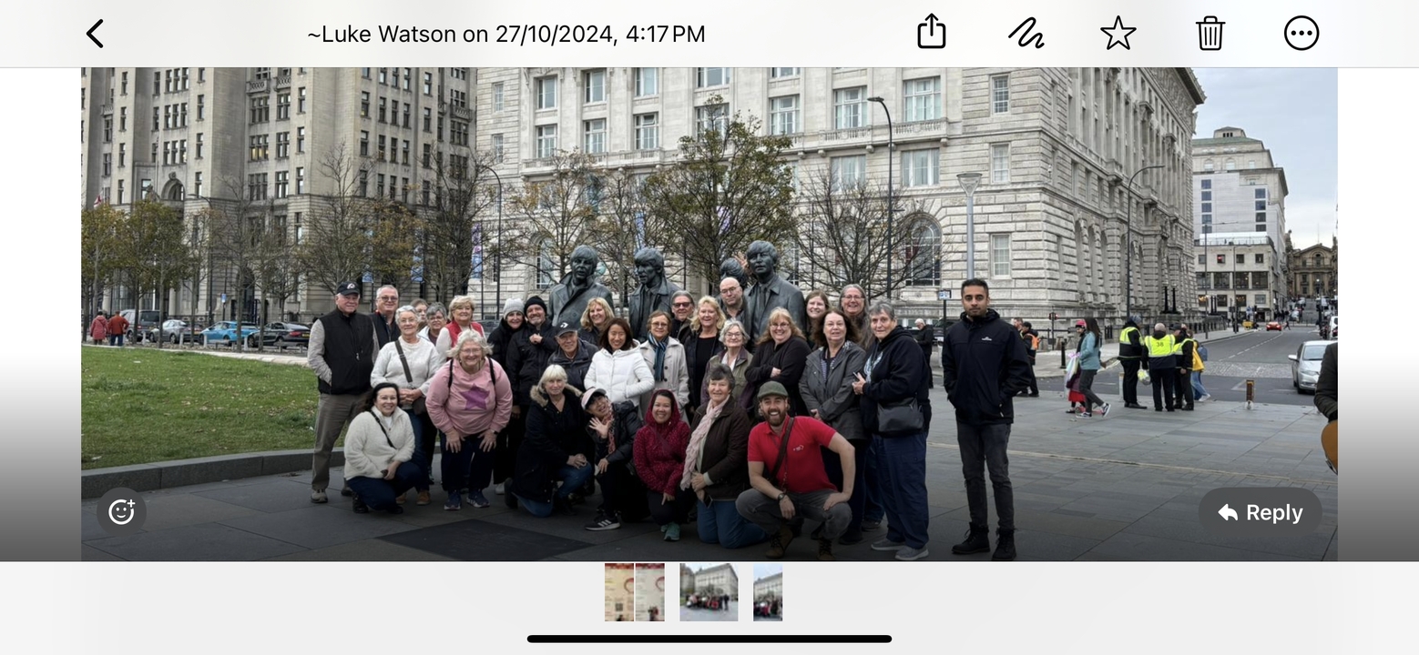 Große Gruppe steht vor Gebäude mit übergelagertem Text, der Details zeigt.