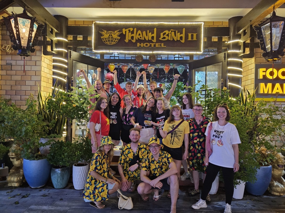 Groupe de personnes posant devant l'entrée d'un hôtel avec des plantes.