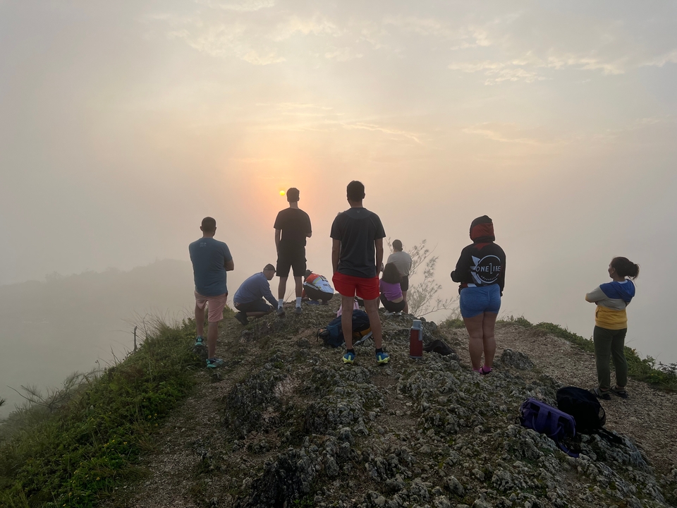 Groupe de personnes regardant le lever du soleil sur une colline.