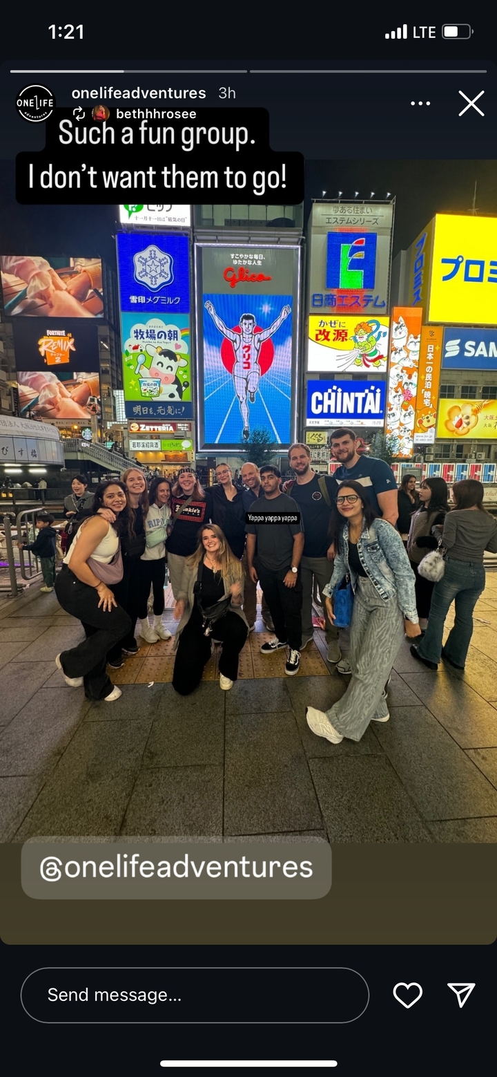 Groupe de personnes posant dans un environnement urbain animé avec des publicités lumineuses.