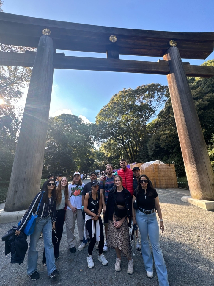 Groupe de personnes posant à l'extérieur avec de grandes portes en bois et des arbres.