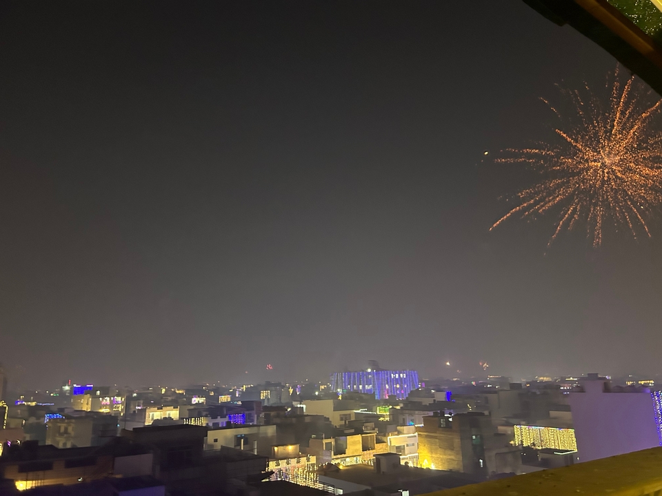 Paysage urbain nocturne avec des feux d'artifice visibles dans le ciel.