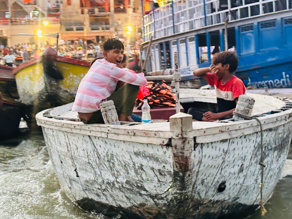 Jongens die lachen en op een boot in een rivier zitten.