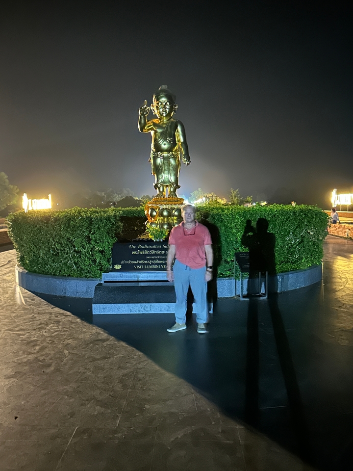 Personne debout devant une statue dorée de Bouddha la nuit.