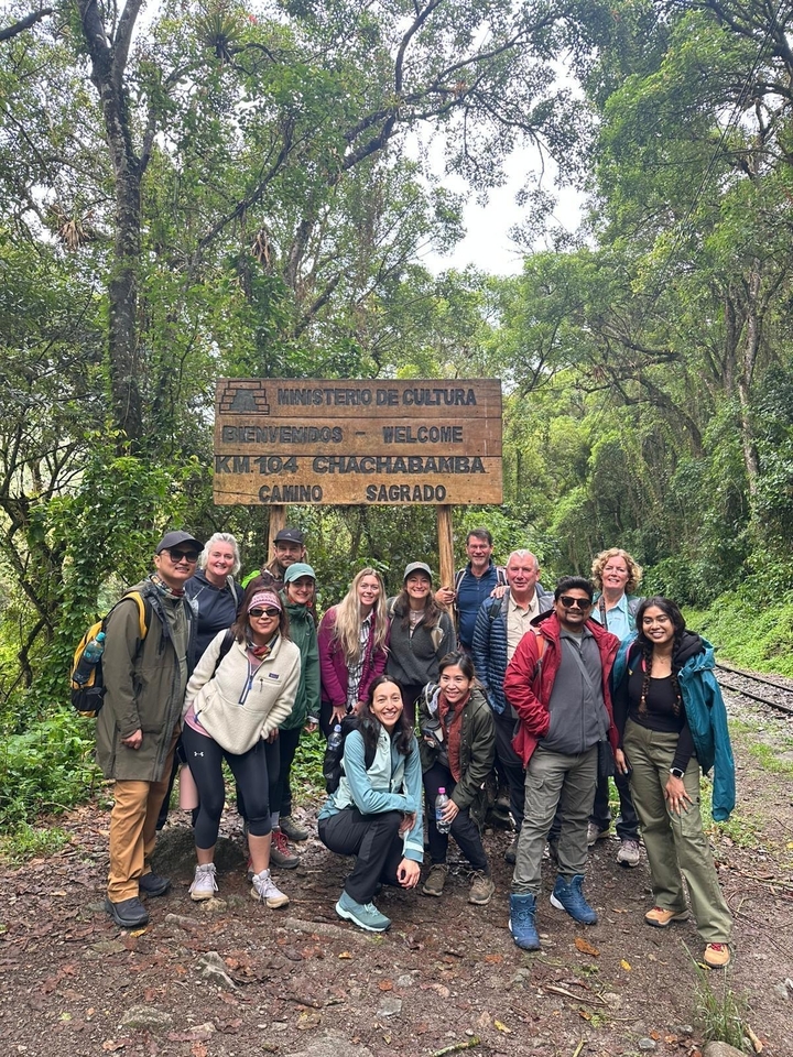 Gruppe von Menschen, die an einem Holzschild in einem Wald posieren.