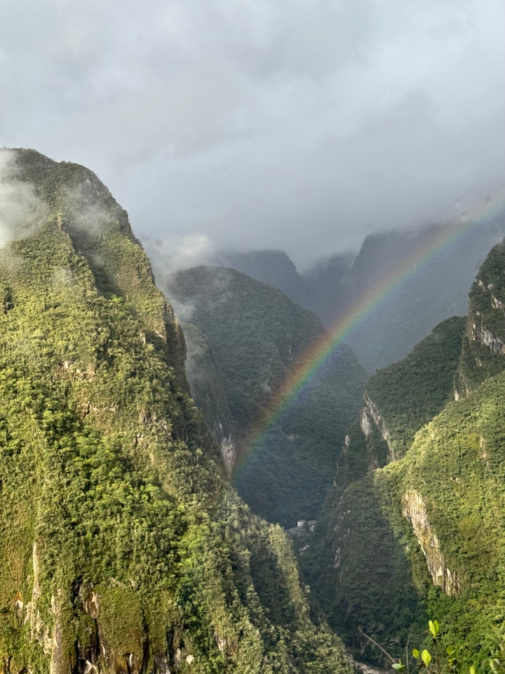 Leuchtender Regenbogen, der sich über üppig grüne Berge wölbt.