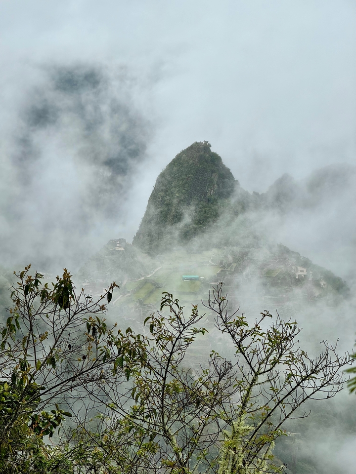 Machu Picchu sichtbar durch Nebel mit üppig grüner Umgebung.