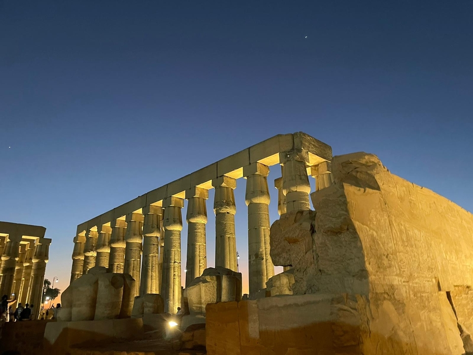 Colonnes antiques illuminées la nuit dans un temple historique.