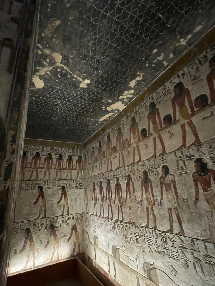 Reliefs peints colorés de figures égyptiennes à l'intérieur d'un tombeau.