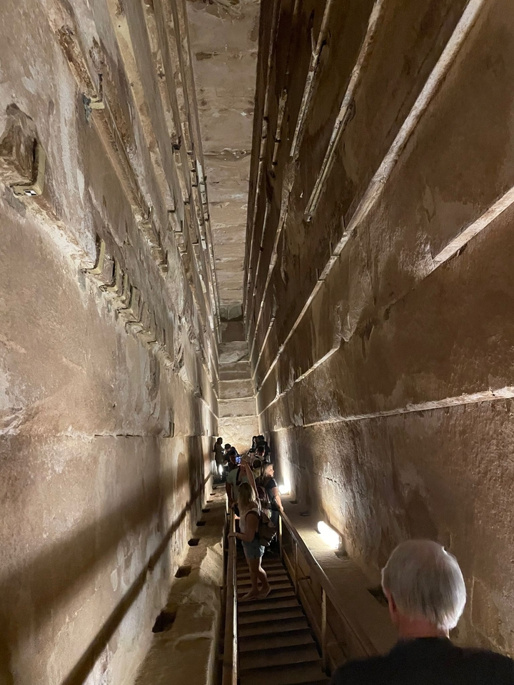 Groupe de touristes marchant dans un étroit couloir de pierre ancien.
