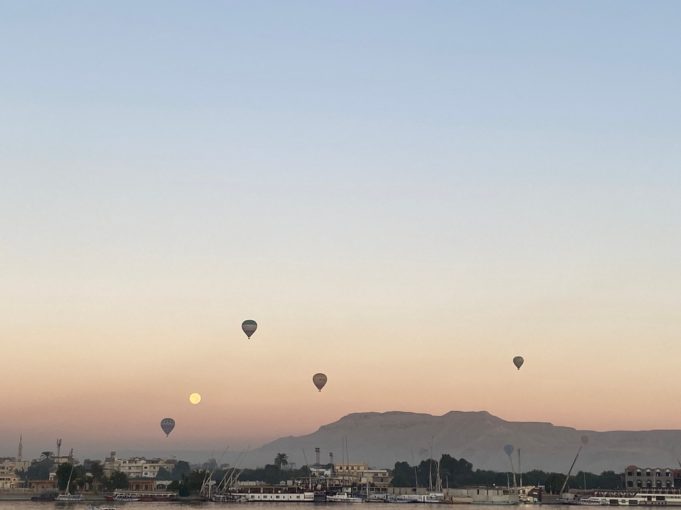 Montgolfières planant au-dessus d'un paysage crépusculaire.