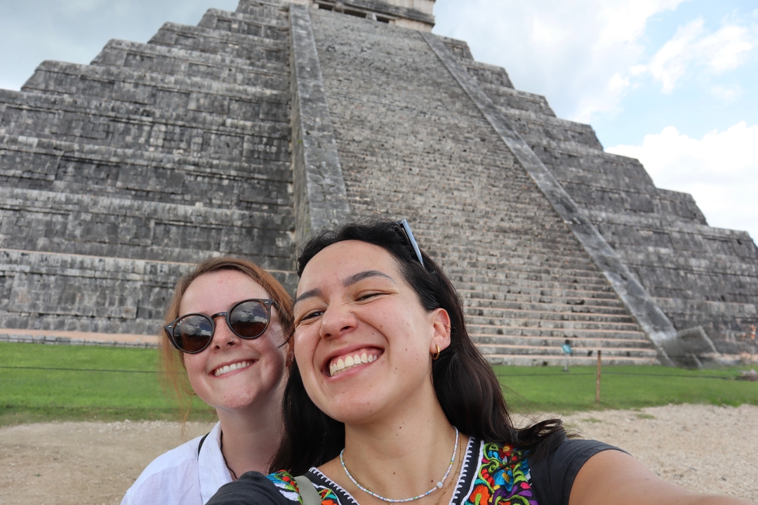 Deux femmes prenant un selfie devant une ancienne pyramide en pierre.
