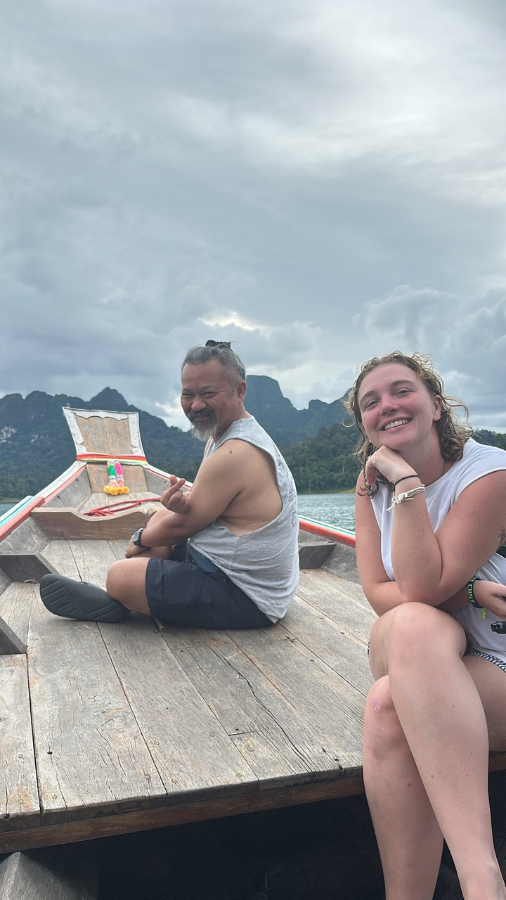 Deux personnes assises sur un bateau avec des montagnes pittoresques en arrière-plan.