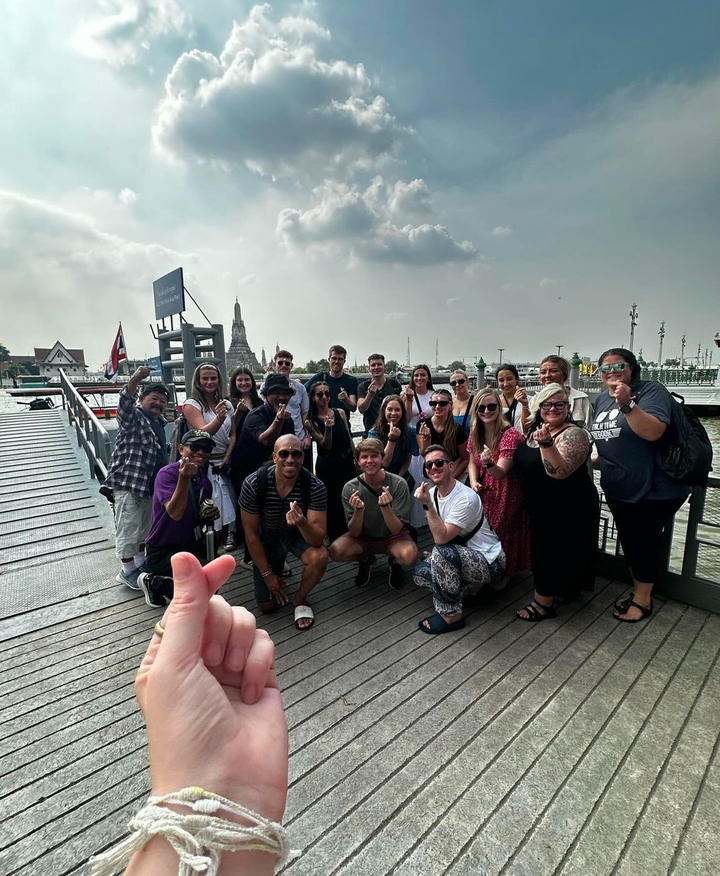 Un grand groupe de personnes posant sur un pont avec un temple visible.