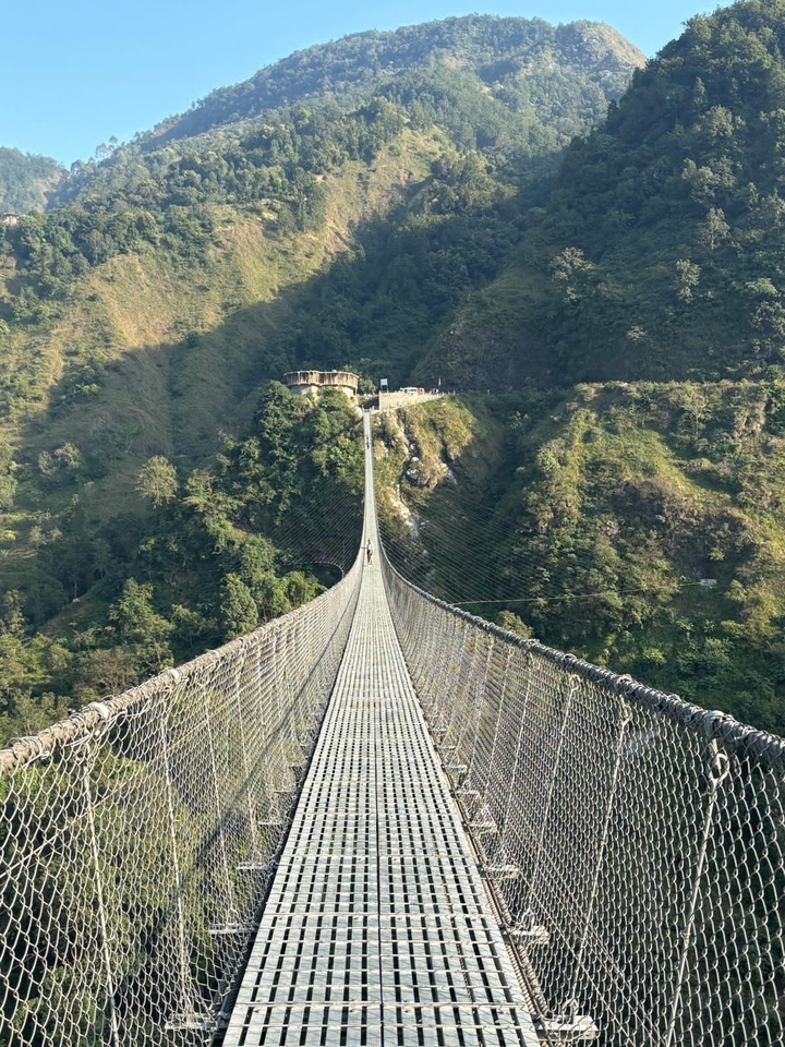Pont suspendu au-dessus de montagnes verdoyantes.