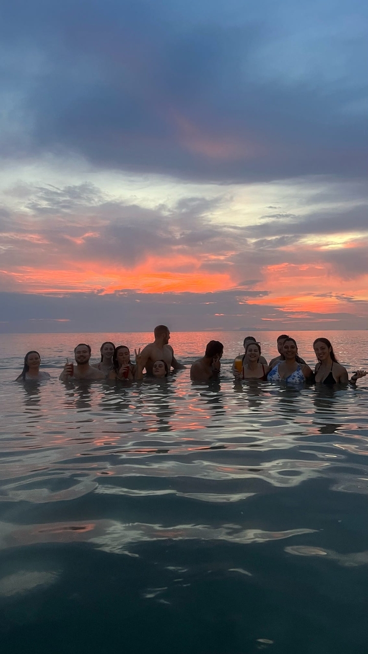 Des gens qui profitent d'une baignade au coucher du soleil dans l'océan.