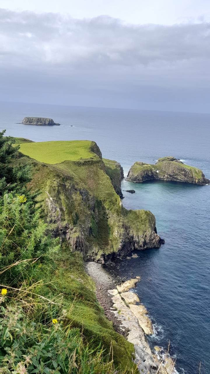 Dramatische Klippe mit grünem Gras mit Blick auf das Meer.