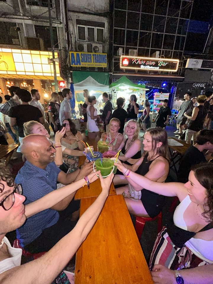 Groupe de personnes assises autour d'une table avec des boissons en souriant.