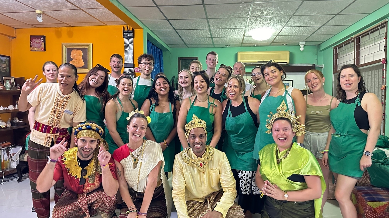 Groupe de personnes en tenue traditionnelle et tabliers posant dans une pièce colorée.