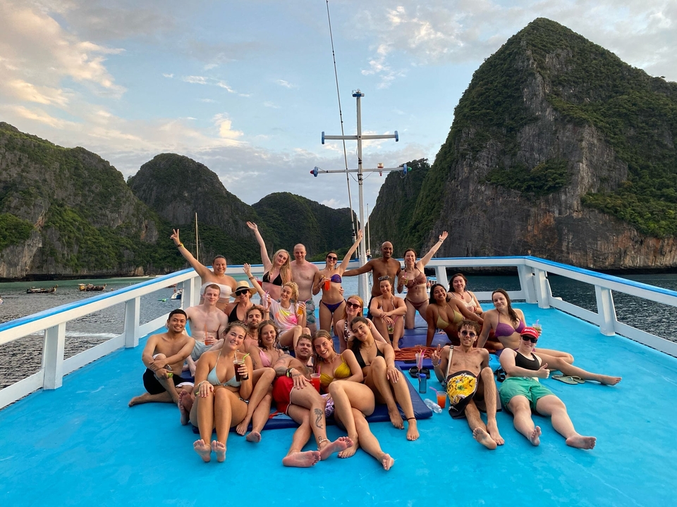 Groupe d'amis sur un bateau avec des falaises d'île en arrière-plan.