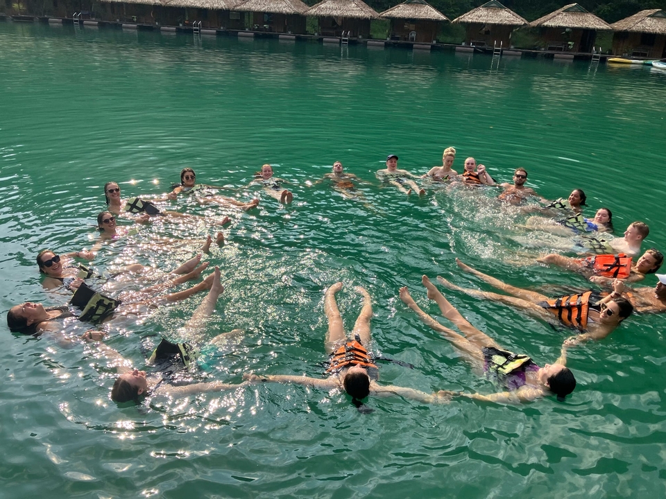Des gens qui flottent et se tiennent la main dans l'eau verte avec des gilets de sauvetage.