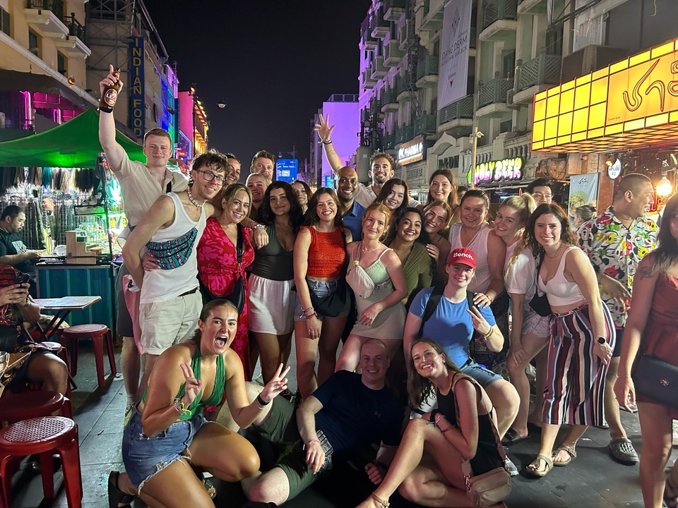 Grand groupe d'amis posant avec enthousiasme dans une rue animée la nuit.
