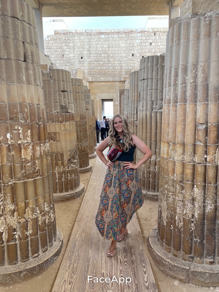 Femme debout parmi des colonnes anciennes avec une pose confiante.