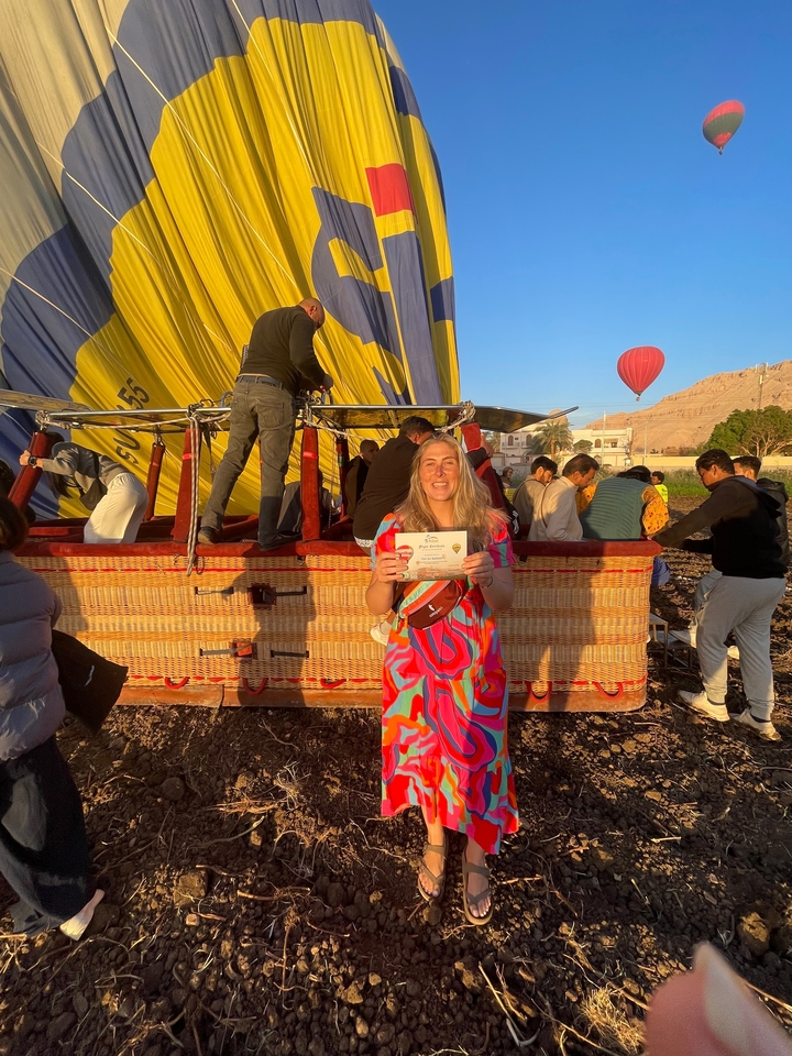 Femme tenant un certificat après l'atterrissage d'une montgolfière.