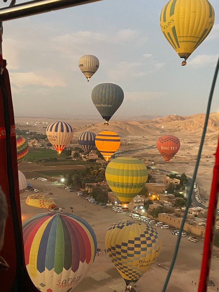 Montgolfières au-dessus d'un paysage désertique avec des collines au loin.