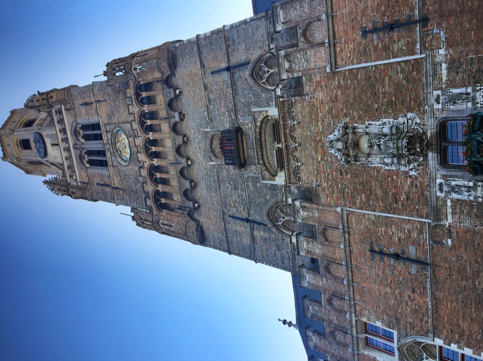 Gros plan sur une grande tour d'horloge aux riches détails architecturaux dans un ciel bleu clair.