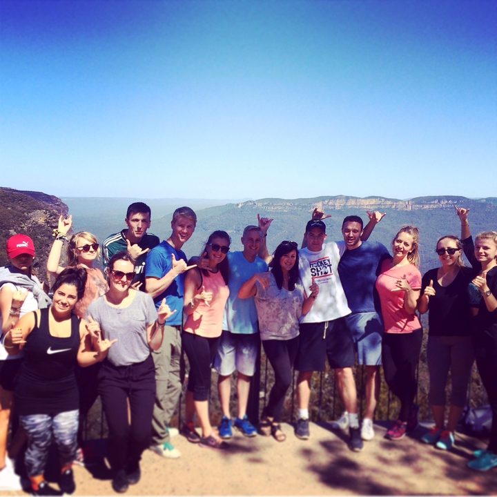 Group of people posing with a scenic cliffside view behind them.