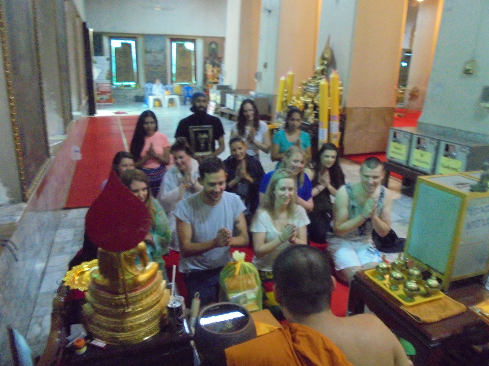 People engaged in a Buddhist prayer session with a monk, inside a temple.