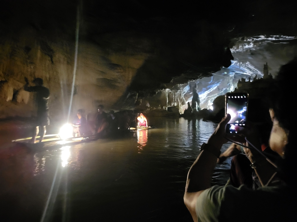 People inside a dark cave, some standing on a small raft.