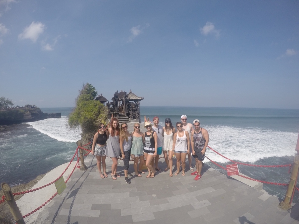 Group posing in front of a temple with the ocean behind.