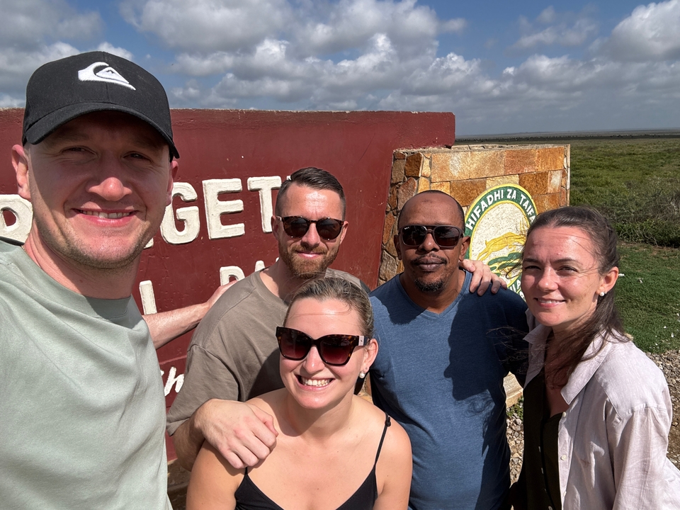 Un groupe de personnes souriantes devant un panneau d'un parc national.