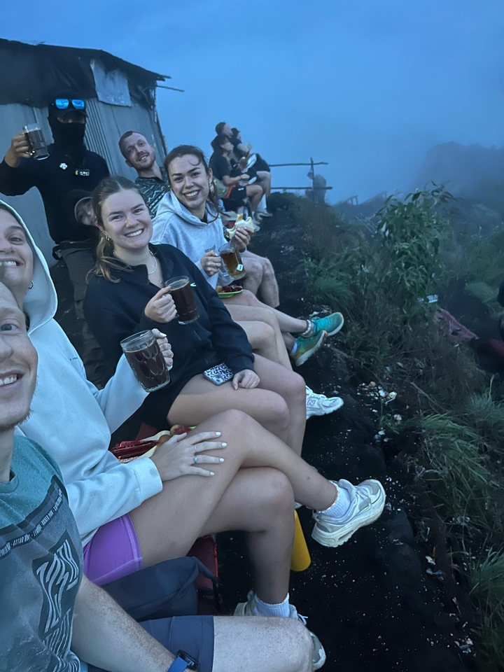 Des gens assis sur un rebord rocheux en train de savourer des boissons.