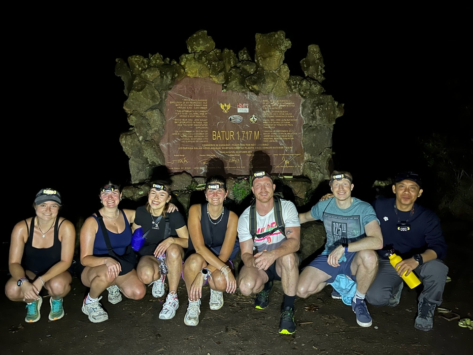 Un groupe de randonneurs au sommet d'une montagne avec un panneau devant.