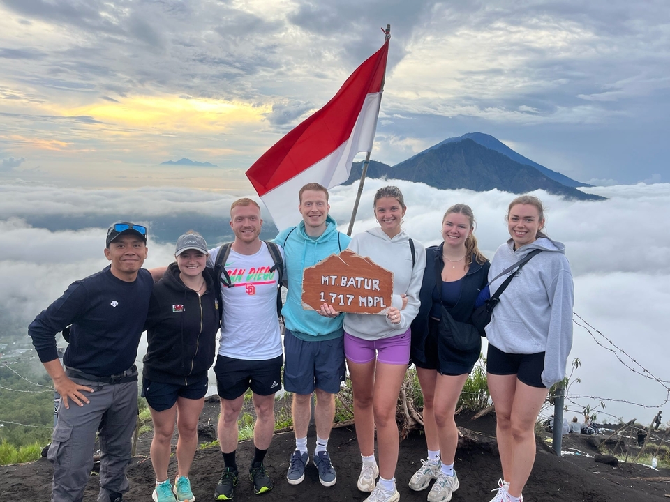 Un groupe de randonneurs posant avec le drapeau indonésien au sommet d'une montagne.
